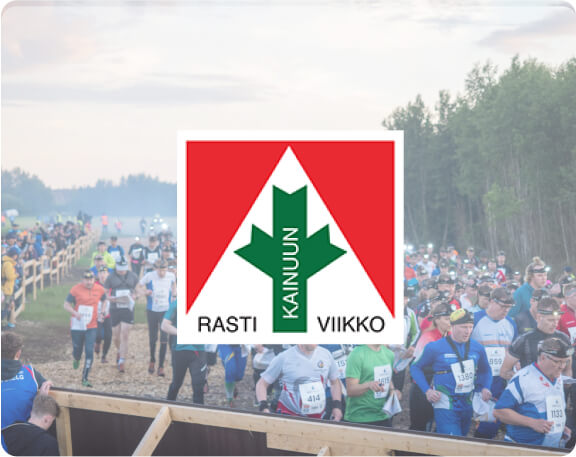 Suuri joukko juoksijoita osallistuu kilpailuun metsäalueen läpi kulkevalla polulla. Rasti-Kainuu-viikon logossa on keskellä vihreä nuoli ja punainen kolmio.